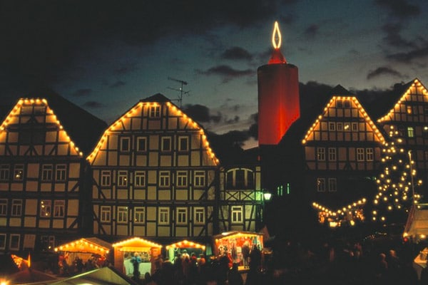 Schlitz - Christmas market with Christmas tree and stalls in front of half-timbered houses and the largest ''advent candle'' in the world, the wrapped keep, evening