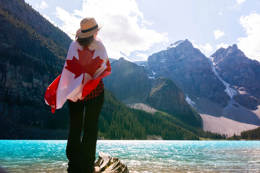 Woman wrapped in Canadian flag looking at mountain